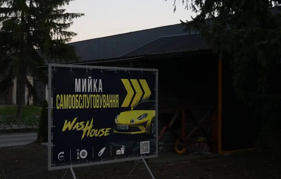 Чорно-жовтий вказівник WashHouse біля в'їзду на автомийку